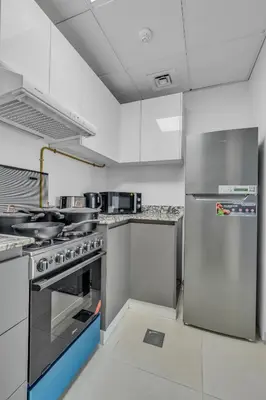 a kitchen with a stove and a refrigerator at Stylish 2BR for 6 with King Beds, Pool, Gym in JVC in Dubai