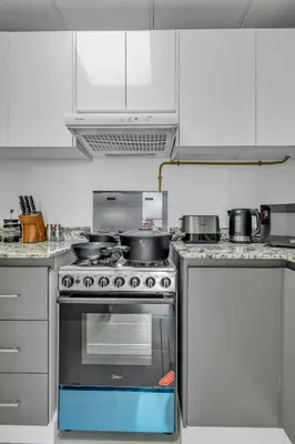 a kitchen with a stove with pots and pans on it at Stylish 2BR for 6 with King Beds, Pool, Gym in JVC in Dubai
