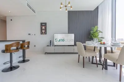a dining room with a table and a tv at Serene and sophisticated Lagoon Living - Suiteable in Dubai