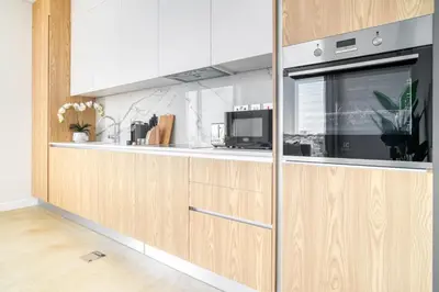 a kitchen with wooden cabinets and a microwave at Stella Stays Al-Barari in Dubai