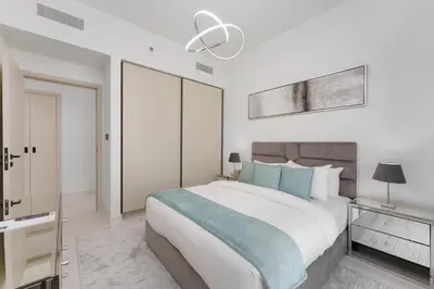 a white bedroom with a large bed with blue pillows at Maison Privee - Exclusive Apt w/ Unmatched Dubai Marina Vistas in Dubai