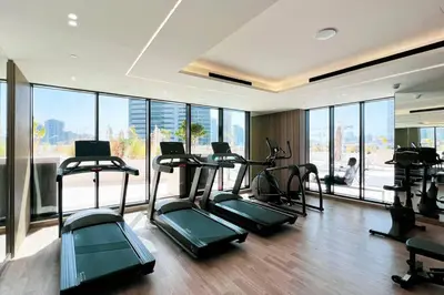 a gym with several treadmills in a room with windows at Fully Furnished Luxe 1BR In JVC in Dubai
