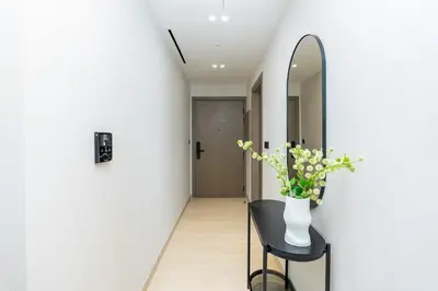a hallway with a mirror and a vase with flowers on a stool at CitiHome - 1BR Freshly Styled and Comfortable in JVC in Dubai