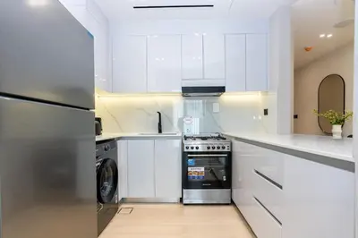 a kitchen with white cabinets and a washer and dryer at CitiHome - 1BR Freshly Styled and Comfortable in JVC in Dubai