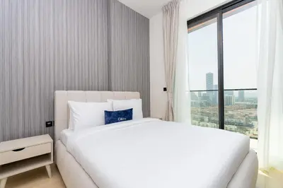 a white bed in a room with a large window at CitiHome - 1BR Freshly Styled and Comfortable in JVC in Dubai