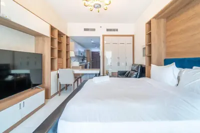 a bedroom with a large white bed and a television at Studio Apartment in Resotz Residence Arjan - Close to Miracle Garden in Dubai