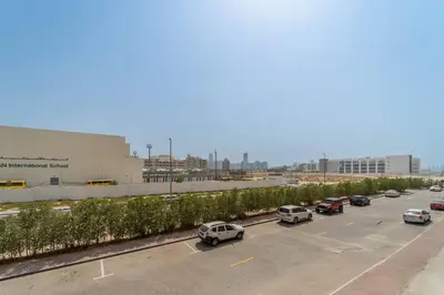 a parking lot with cars parked in front of a building at Studio Apartment in Resotz Residence Arjan - Close to Miracle Garden in Dubai