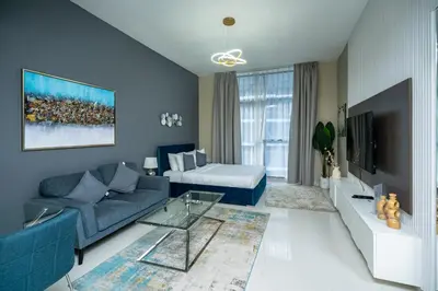 a living room with a blue couch and a tv at Escape24 Studio at Loreto with Community View in Dubai