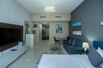 a living room with a blue couch and a tv at Escape24 Studio at Loreto with Community View in Dubai