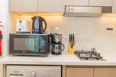 a kitchen counter with a microwave and a stove at Bloomfields Cozy Stu Azizi Riviera Meydan in Dubai