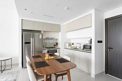a kitchen and dining room with a wooden table and chairs at Family Friendly 2BDR With Sea & City View in Dubai