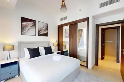 a bedroom with a large white bed and a bathroom at Silverene Tower B - Bright Two Bedroom in Dubai