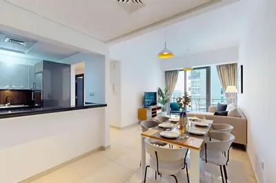 a kitchen and a living room with a table and chairs at Silverene Tower B - Bright Two Bedroom in Dubai