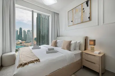 a bedroom with a large white bed with a large window at Luxury 4BR Burj Khalifa & Fountain Views in Dubai