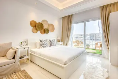 a white bedroom with a large bed and a window at Studio Apartment in Vincitore Palacio Arjan in Dubai