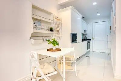 a white kitchen with a white table and a plant at Studio Apartment in Vincitore Palacio Arjan in Dubai