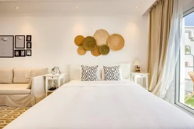 a white bedroom with a large bed and a couch at Studio Apartment in Vincitore Palacio Arjan in Dubai