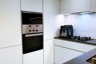 a white kitchen with a stove and a microwave at Brand New 1 Bedroom Apartment JVC in Dubai