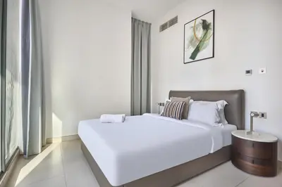 a white bedroom with a large bed and a table at Luxury Living in Marina Liv Residence 2BR in Dubai