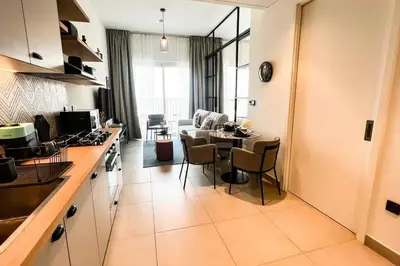 a kitchen and living room with a table and chairs at Brand New Apartment in Socio Tower Dubai Hills in Dubai