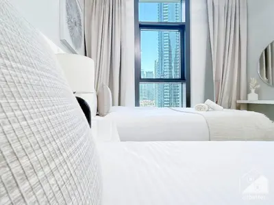 a white bedroom with two beds and a window at Luxury Burj Crown 4bedroom Balcony & Downtown View in Dubai