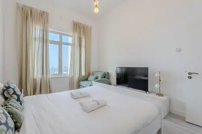 a white bedroom with a bed and a television at Al Hatimi, Shoreline Apartments, Palm Jumeirah, Dubai in Dubai