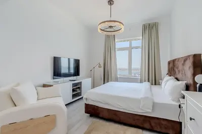 a bedroom with a bed and a couch and a tv at Al Hatimi, Shoreline Apartments, Palm Jumeirah, Dubai in Dubai