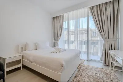 a bedroom with a white bed and a large window at Modern and Cozy Studio in JVC I Luma Building in Dubai