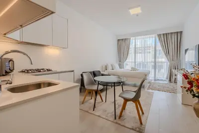 a kitchen and living room with a table and chairs at Modern and Cozy Studio in JVC I Luma Building in Dubai