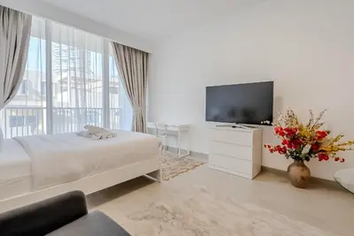 a white room with a bed and a television at Modern and Cozy Studio in JVC I Luma Building in Dubai