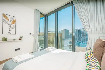 a bedroom with a bed and a large window at Vacay Lettings - Waves Grande - Sobha Hartland in Dubai