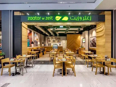 a restaurant with wooden tables and chairs and a sign at Vacay Lettings - Waves Grande - Sobha Hartland in Dubai