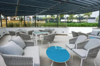 a patio with couches and tables and chairs at Vacay Lettings - Waves Grande - Sobha Hartland in Dubai