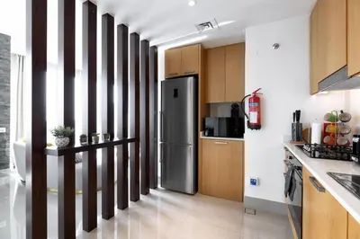a kitchen with a stainless steel refrigerator and wooden cabinets at Opera Grand by Emaar LUXURY 1 BR Apartment in Downtown Dubai sea and city view in Dubai