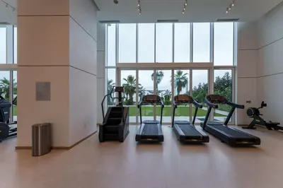 a gym with four tread machines in a room with windows at Beachfront Luxury Living at La Vie Residence JBR in Dubai