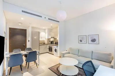 a living room with a couch and a table and chairs at Sobha Creek Vistas Cozy 1BDR with balcony in Dubai