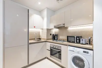 a kitchen with white cabinets and a washer and dryer at Sobha Creek Vistas Cozy 1BDR with balcony in Dubai