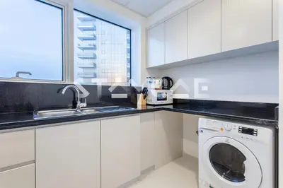 a kitchen with white cabinets and a washing machine at Staycae Holiday Homes - Carson Towers in Dubai