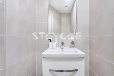 a white bathroom with a sink and a mirror at Staycae Holiday Homes - Carson Towers in Dubai