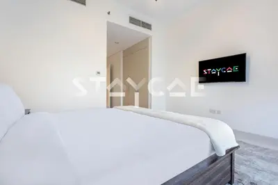 a bedroom with a bed and a tv on the wall at Staycae Holiday Homes - Carson Towers in Dubai