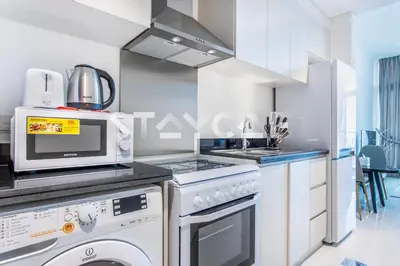a kitchen with a stove and a microwave at Staycae Holiday Homes - Carson Towers in Dubai