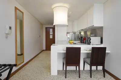 a kitchen with a white counter and two chairs at Maison Privee - Fabulous Studio with Direct Burj Khalifa Views in Dubai