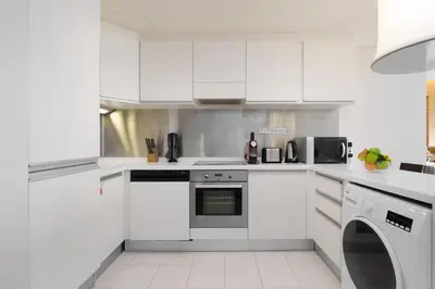 a white kitchen with white cabinets and appliances at Maison Privee - Fabulous Studio with Direct Burj Khalifa Views in Dubai