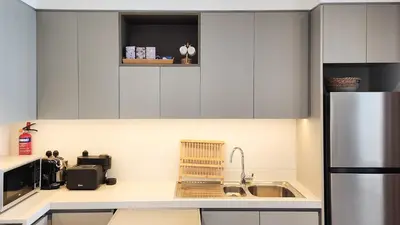 a kitchen with white cabinets and a stainless steel refrigerator at Chic New 2BR Dubai Creek Gate by Tanami Holiday Homes in Dubai