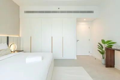a bedroom with white walls and a white bed at Ahlan HH - Luxurious 1BR Suite at La Vie - Free Private Beach Access in Dubai