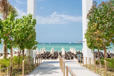 a pathway to the beach with chairs and umbrellas at Ahlan HH - Luxurious 1BR Suite at La Vie - Free Private Beach Access in Dubai