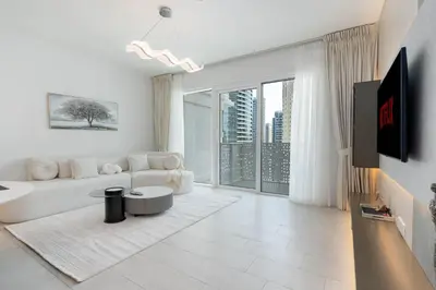 a living room with a white couch and a large window at Ahlan HH - Luxurious 1BR Suite at La Vie - Free Private Beach Access in Dubai