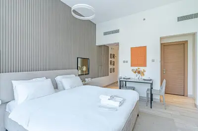a bedroom with a large white bed and a desk at Elegant Studio Stay I Pool, Gym & Parking in Dubai