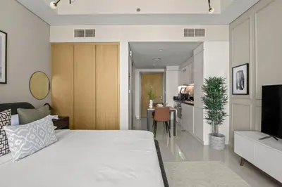 a bedroom with a large white bed and a kitchen at GuestReady - Contemporary studio in Business Bay in Dubai