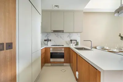 a kitchen with white counters and wooden cabinets at GuestReady - Glamorous place near Burj Khalifa in Dubai